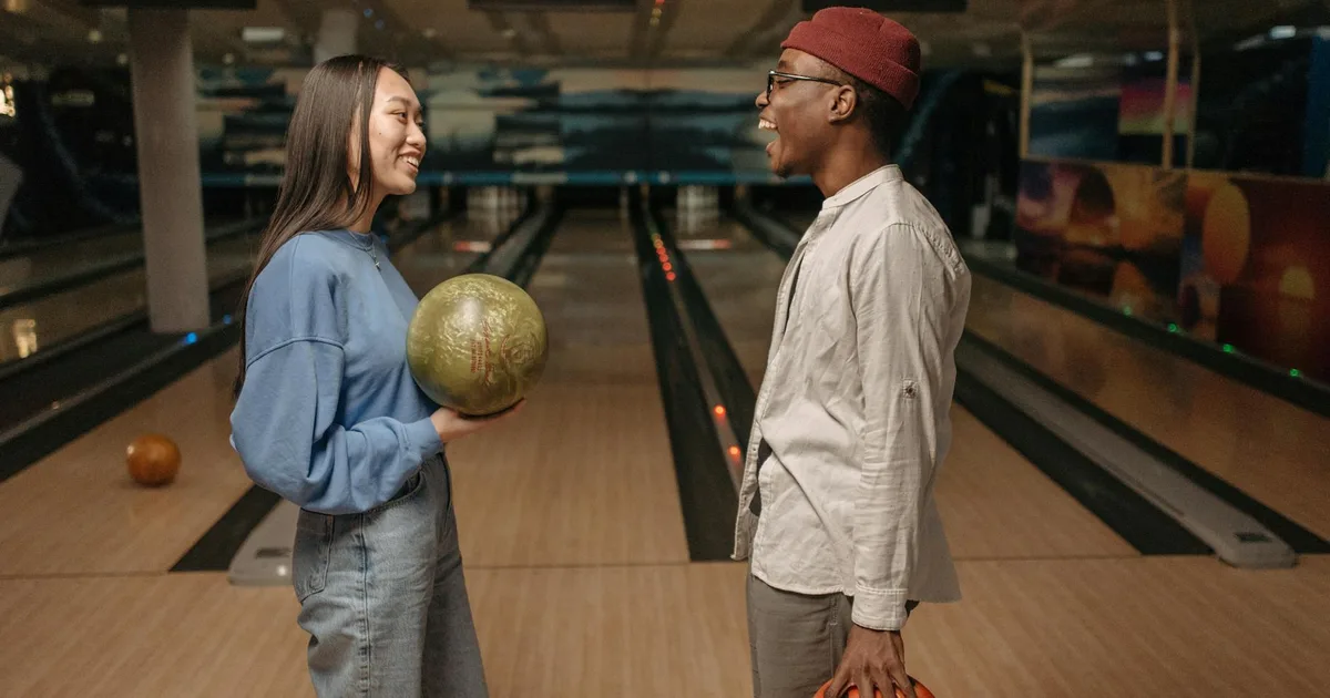 Bowler releasing ball down a bowling lane toward pins