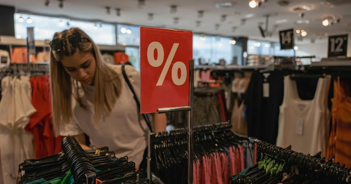 Shopper browsing liquidation store shelves stacked with discounted merchandise